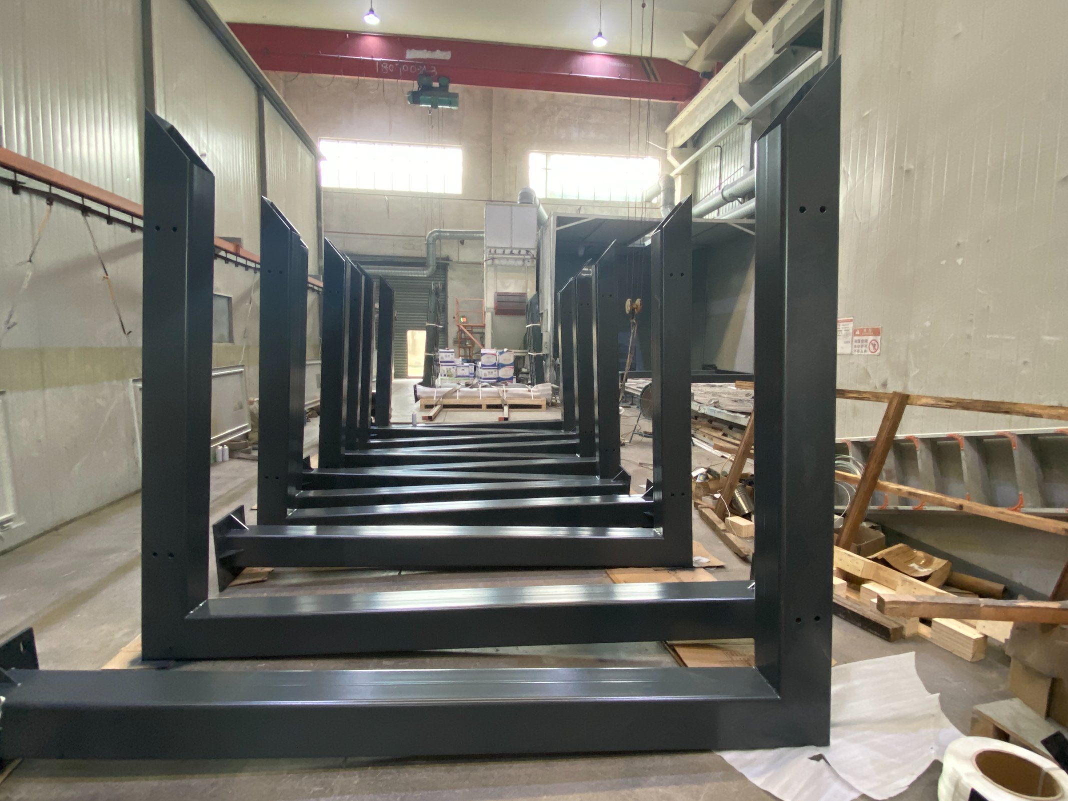 Black powder-coated pergola frames lined up in the Hannah workshop