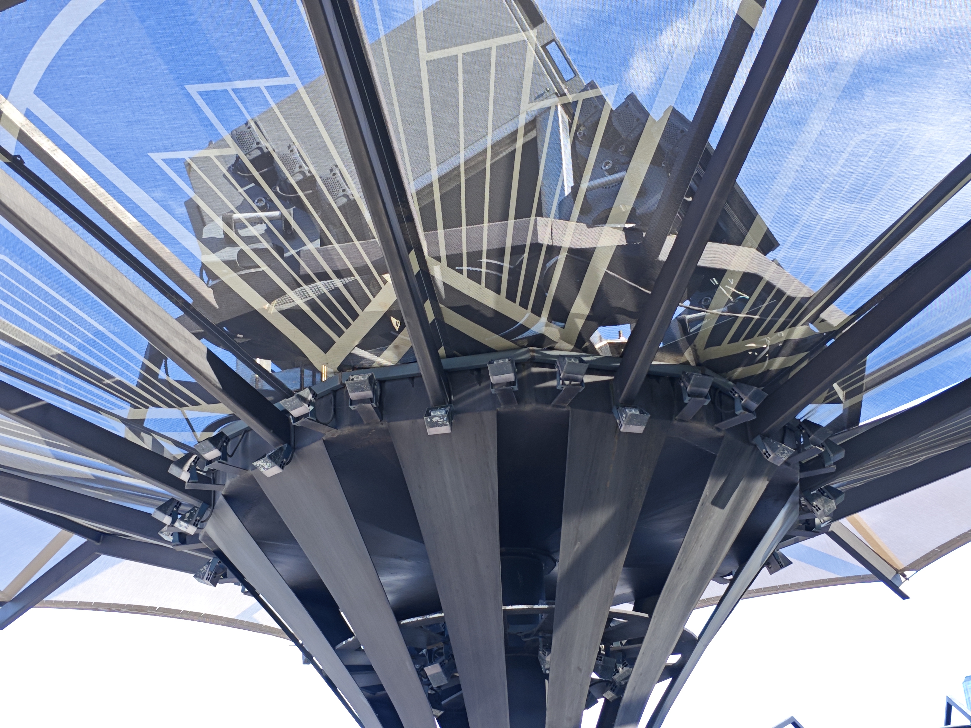 Underside of a circular transparent-roof pergola showing the radiating ribs