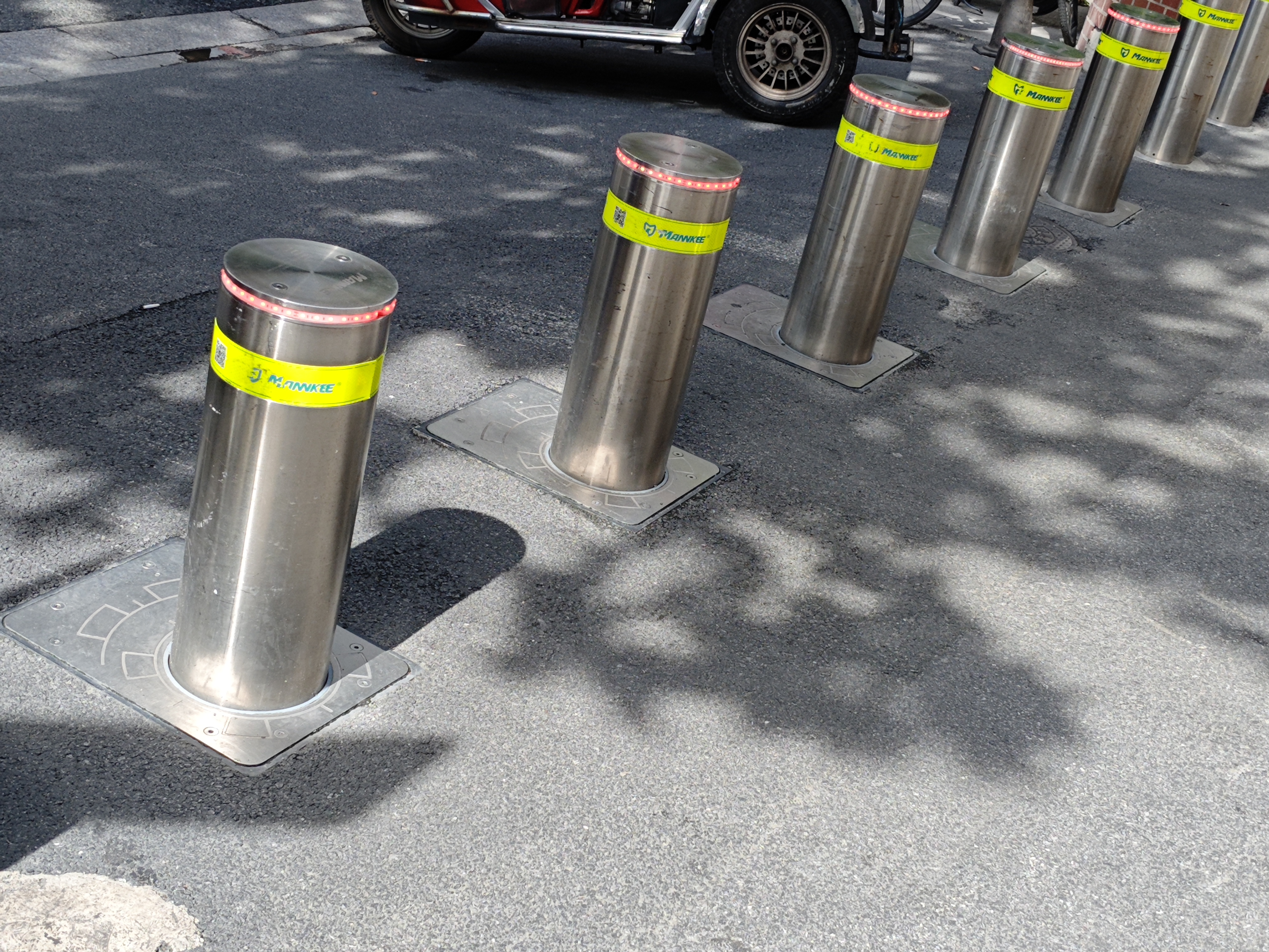 Row of stainless steel bollards with reflective bands along a road