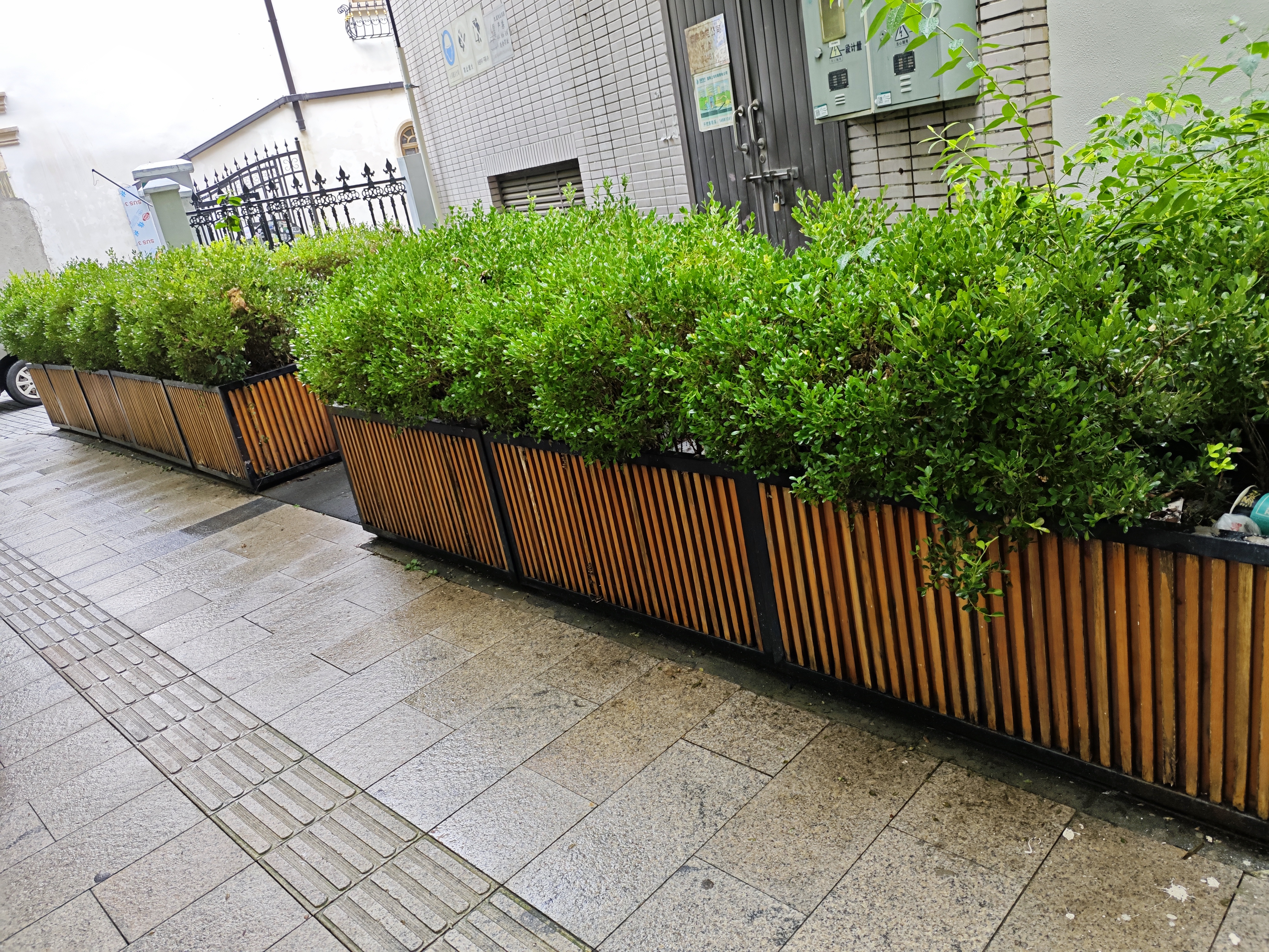 Wood-slat metal planter boxes along a paved street