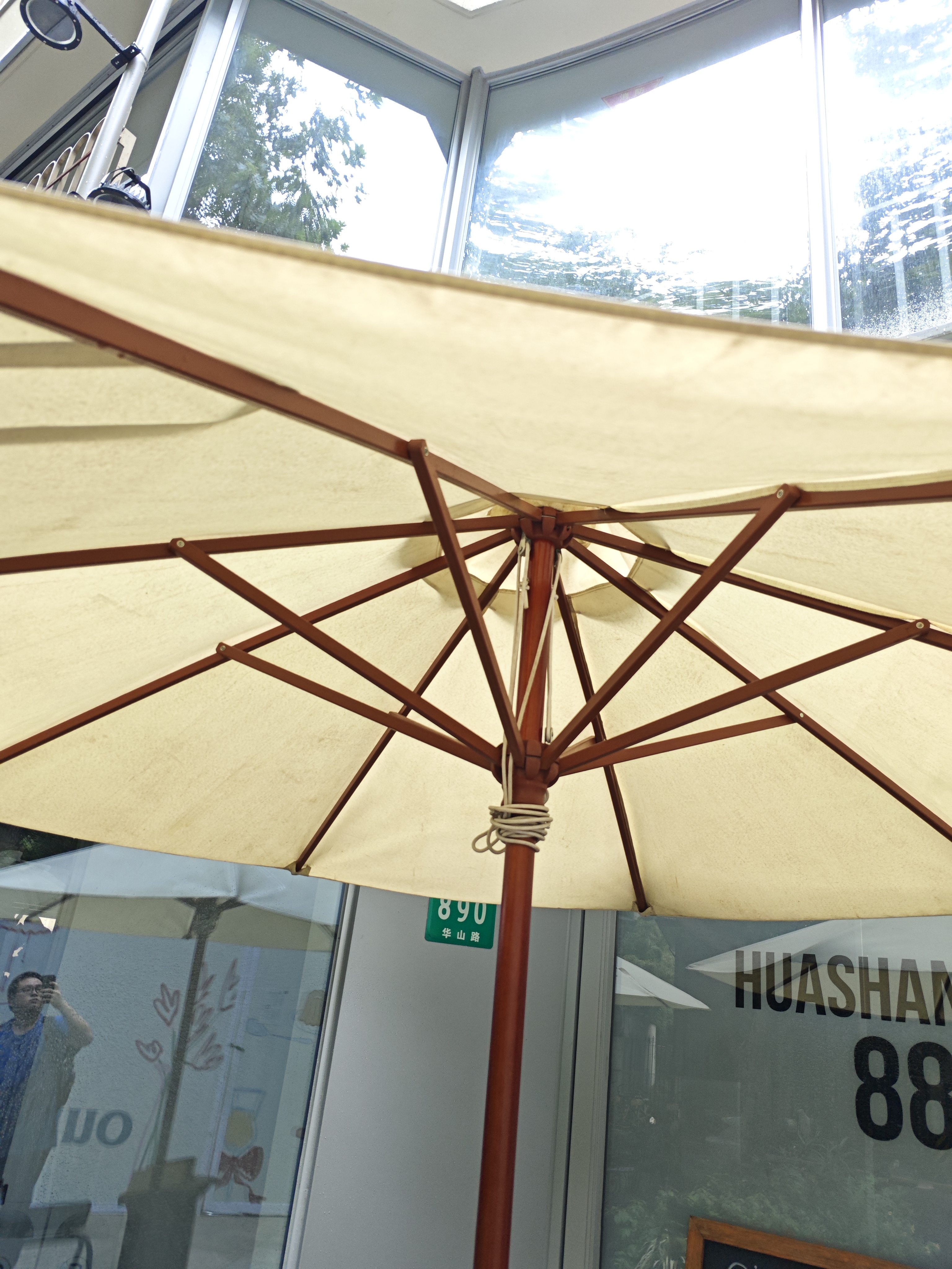 Parasol canopy supported by wooden-handled metal ribs